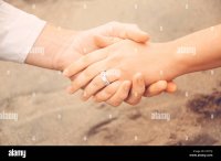 manos-en-la-playa-una-nueva-pareja-mostrando-su-anillo-de-compromiso-e57t0j.jpg
